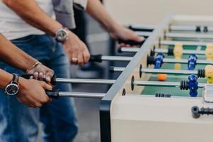 bästa manliga vänner spelar bordsfotboll eller kricker, känner värme i väntan på seger. sport, vänskap, underhållning, fritid koncept foto