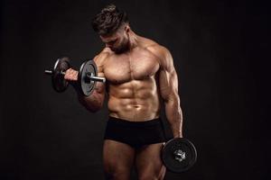 muskulös kroppsbyggare som gör övningar med hantlar