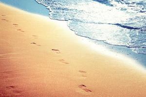 gå på stranden och lämna fotspår i sanden. foto