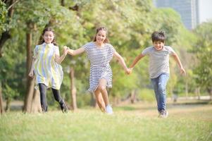 en halv-thai-indisk pojke och en halv-thai-europeisk flickvän tävlar i en park medan de lär sig utanför skolan foto