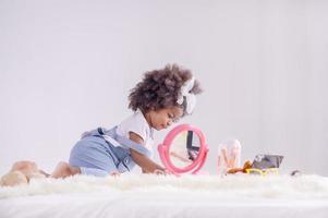 en söt liten afrikansk flicka spelar glatt sminktillbehör i sitt sovrum foto