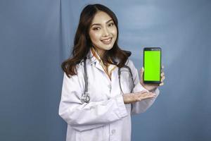ung asiatisk kvinna läkare pekar och visar grön skärm eller kopiera utrymme på sin smartphone foto