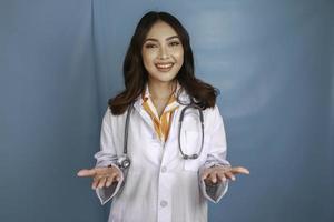 ung läkare kvinna presenterar en idé medan tittar leende på isolerade blå bakgrund foto