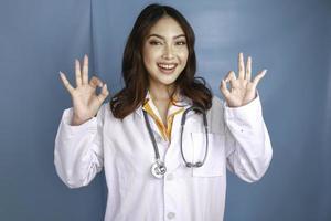 ung asiatisk kvinna läkare ler och visar ok tecken. foto