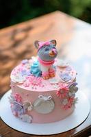 festlig rosa tårta med en katt på toppen. foto