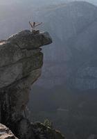 ung man höjer sina armar vid kanten av branta klippor i Yosemite nationalpark foto