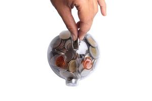 kvinnlig hand att sätta mynt i spargris på vit bakgrund. pengar att spara koncept. foto