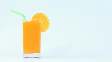 ett glas apelsinjuice med färsk bit skivad frukt och pipa i den på vit bakgrund foto