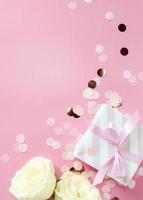 presentförpackning och rosenblommor på rosa bakgrund. glad alla hjärtans dag, mors dag, födelsedag koncept. romantisk platt lekmannakomposition. foto