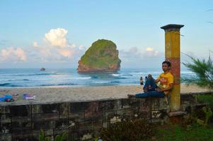 malang, östra java, indonesien, 2022 - strandlandskap med människor som lutar sig mot det kinesiska grottans strandstaket i malang, östra java foto