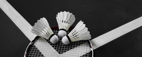 badmintonsportutrustning, fjäderbollar, racket, grepp, på golvet på inomhusbadmintonbanan. foto