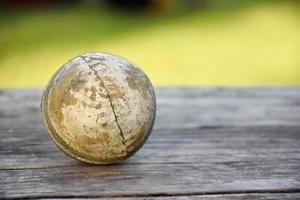 gammal träningsutrustning för cricketsport på mörkt golv, läderboll, wickets, hjälm och träslagträ, mjukt och selektivt fokus, koncept för traditionella cricketsportälskare runt om i världen. foto