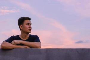 asiatisk man stanna ensam med himmel bakgrund. känslor uttryck och mental hälsa koncept. foto