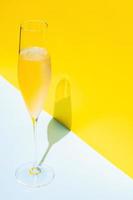 ett glas kall champagne med ånga som har skugga från solljus på blå och gul bakgrund. sommar koncept. foto