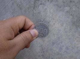 en man som håller ett mynt på 500 rupiah i indonesisk valuta foto