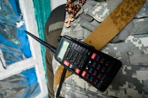 walkie-talkie och radband med ett kors i en soldats bröstkorg, krig och gudstro. foto
