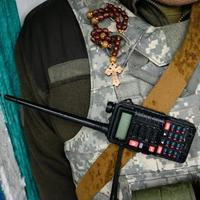 walkie-talkie och radband med ett kors i en soldats bröstkorg, krig och gudstro. foto