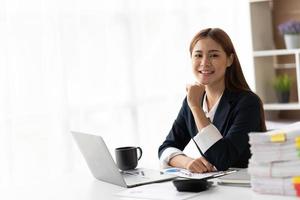porträtt av leende vacker asiatisk affärskvinna som arbetar på kontoret använder dator med kopia utrymme. företagsägare människor sme frilansande marknadsföring online e-handel telemarketing, arbeta hemifrån koncept foto