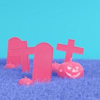 rosa halloweenpumpor med kors och gravstenar på klarblå bakgrund i pastellfärger. minimalism koncept foto