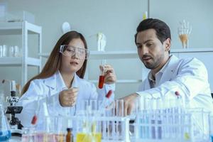 attraktiv forskare medicinsk arbetare med provrör på laboratoriet, gör en analys i ett laboratorium som gör forskning för att skapa ett vaccin och utveckling foto