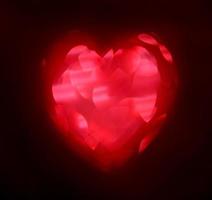 röd oskärpa hjärta form av ljus bokeh på en svart bakgrund foto