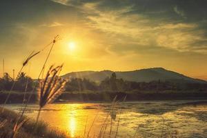 natur med berg floder gräs ljuset av solnedgången foto