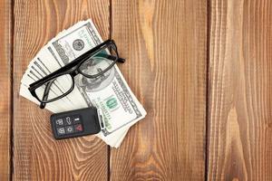 pengarkassa, glasögon och bilfjärrnyckel på träbord foto