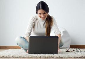 vacker ung kvinna som arbetar på sin bärbara dator hemma.