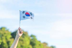 hand som håller korea flaggan på natur bakgrund. national foundation, gaecheonjeol, allmän nationshelgdag, Koreas nationella befrielsedag och glada firandekoncept foto