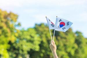 hand som håller korea flaggan på natur bakgrund. national foundation, gaecheonjeol, allmän nationshelgdag, Koreas nationella befrielsedag och glada firandekoncept foto