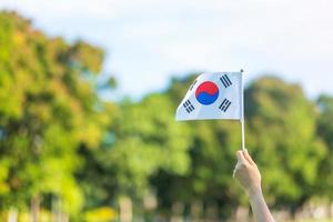 hand som håller korea flaggan på natur bakgrund. national foundation, gaecheonjeol, allmän nationshelgdag, Koreas nationella befrielsedag och glada firandekoncept foto
