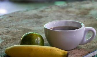 en kopp kaffe och frukt. foto