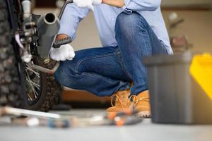 mekaniker fixar motorcykel i verkstadsgarage, man som reparerar motorcykel i verkstad, reparations- och underhållskoncept foto