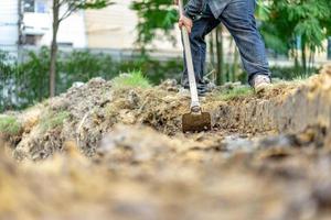 trädgårdsmästare gräver jorden med sin utrustning för trädgårdsarbete och förbereder mark för plantering. foto