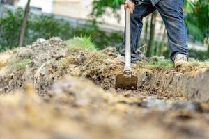 trädgårdsmästare gräver jorden med sin utrustning för trädgårdsarbete och förbereder mark för plantering. foto