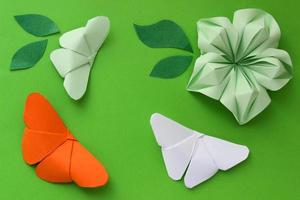 origami papper bakgrund med fjärilar, blommor och blad. origami sammansättning. pappershantverk foto