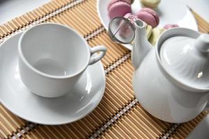porslinstekanna med en kopp te och makroner foto