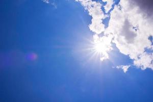 realistisk lysande sol med linsutflytning. blå himmel med moln foto
