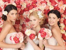 tre kvinnor med bakgrund fulla av rosor foto