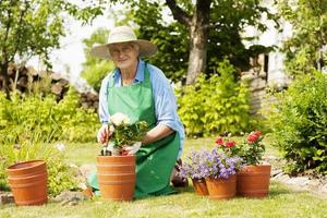 äldre kvinna med blommor i trädgården
