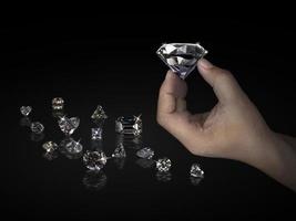 hand som håller diamant isolerad på svart bakgrund. koncept för att välja bästa diamantpärla foto