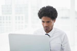 koncentrerad affärsman som tittar på sin bärbara dator foto