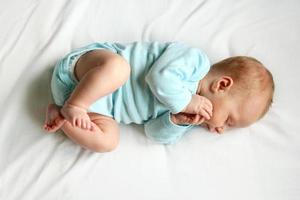 sött nyfött barn som sover på vit säng foto