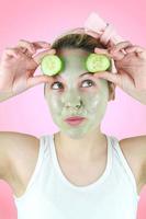 rolig kvinna som bär en grön ansiktsmask och gurkor. foto