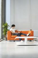 man använder bärbar dator på orange soffa på kontoret