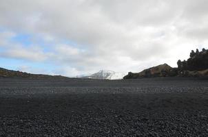 fantastisk utsikt över snötäckta berg från svart sandstrand foto