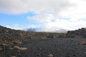 natursköna snötäckta berg från en svart sandstrand foto