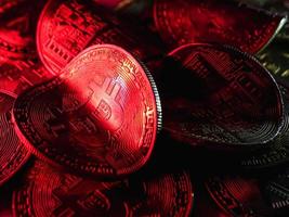 vridna mynt med bitcoin-symbol på rött ljus. begreppet en kris på kryptovalutamarknaden. foto