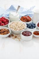 havreflingor och olika ingredienser till frukost på det vita bordet foto