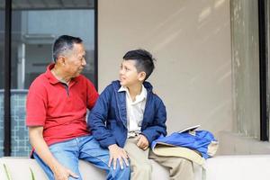 farfar ger råd till sitt barnbarn, efter skolan på gården. föräldraskap och familjeaktivitet koncept. foto